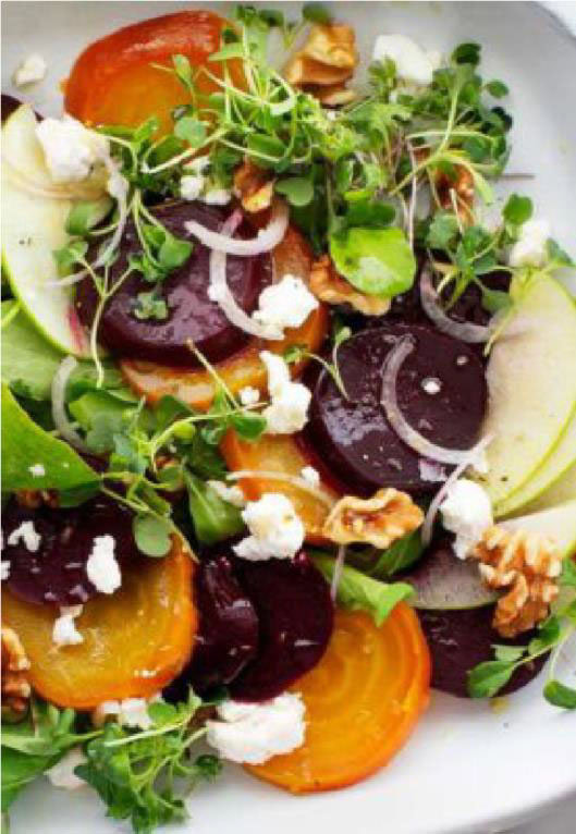 Discover how to make roasted beet salad with sliced beets, apple slices, crumbled cheese, walnuts, arugula, and microgreens, all elegantly served on a white plate.