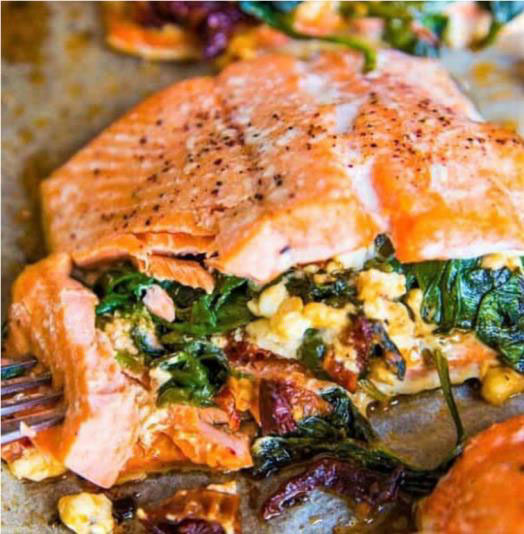 Learn how to make stuffed baked salmon fillets with a delicious blend of spinach, sun-dried tomatoes, and cheese, all perfectly grilled on a baking sheet.